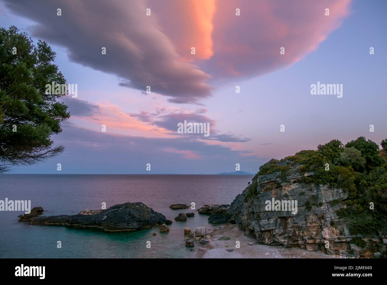 Sunset Clouds Over a Small Rocky Beach Stock Photo - Alamy