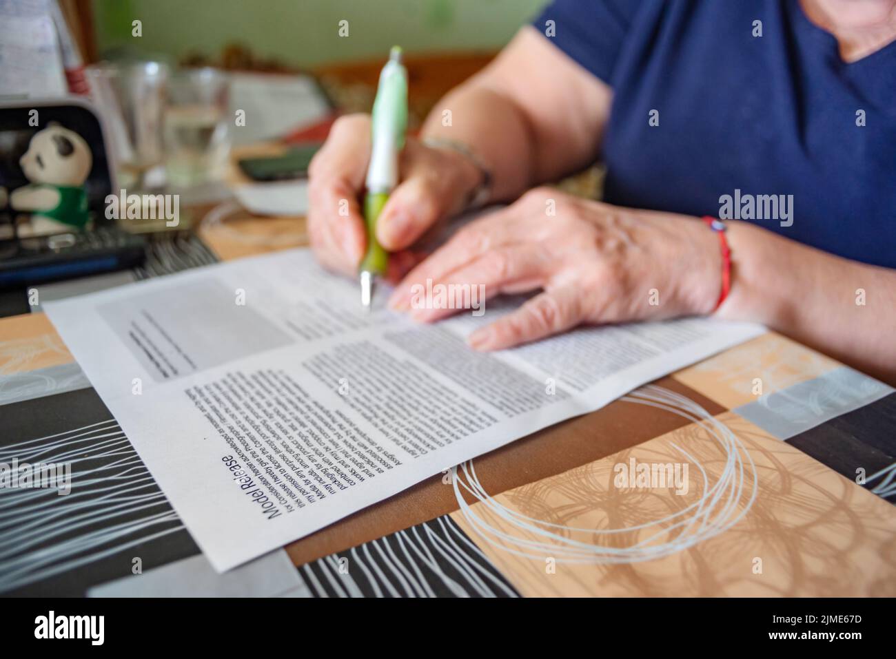 Model Release Form is Being Signed by Hands of an Elderly Woman at Home Stock Photo