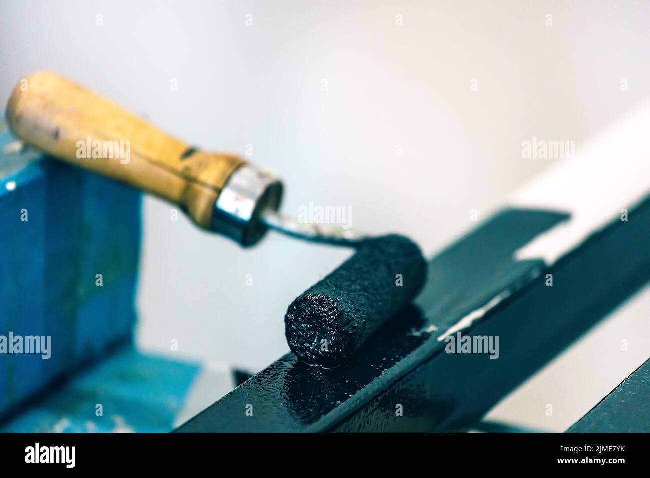 Painting of metal profile with paint roller. Workshop for anti-corrosion metal processing Stock Photo