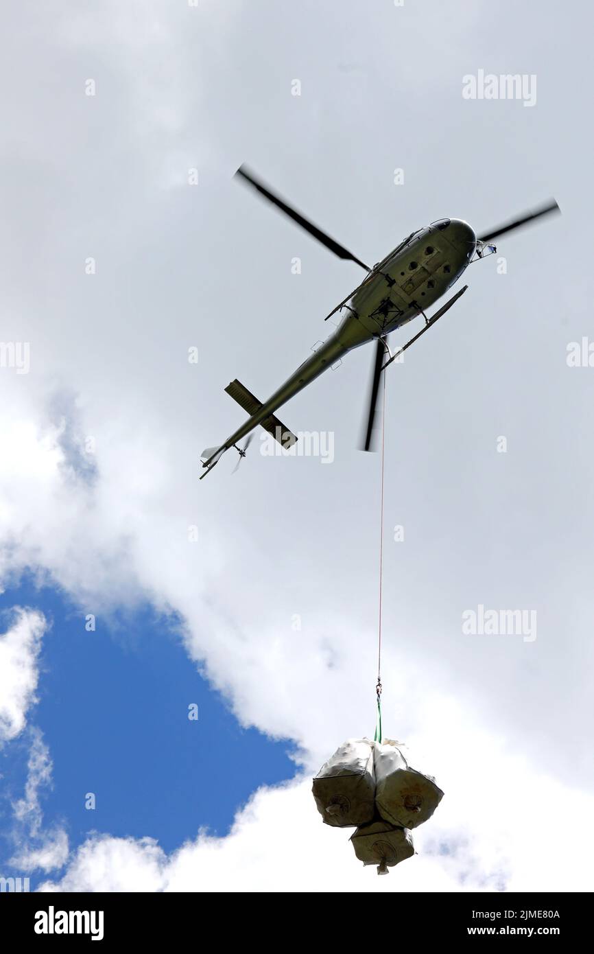 helicopter carrying material attached to a long hook Stock Photo Alamy