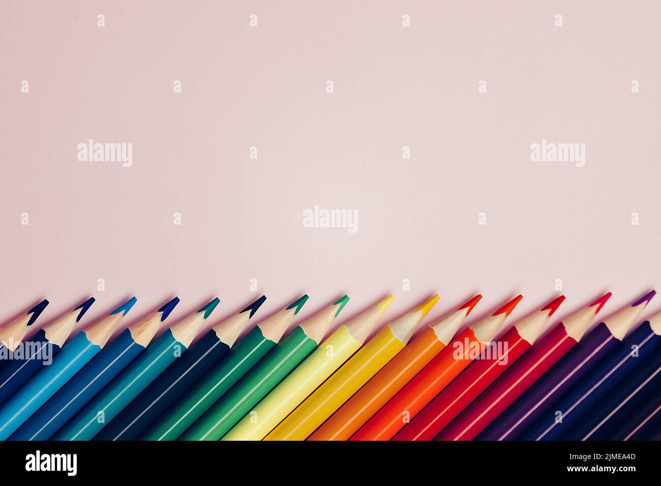 Colored pointed pencils lie on a pink background with space for copying ...
