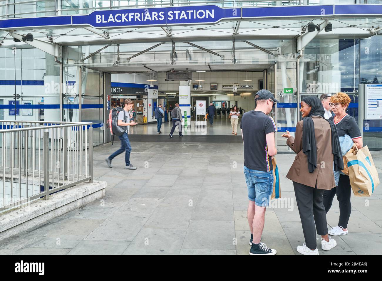 A female streeet hawker accosts a man outside Blackfriars rail station, London, England. Stock Photo