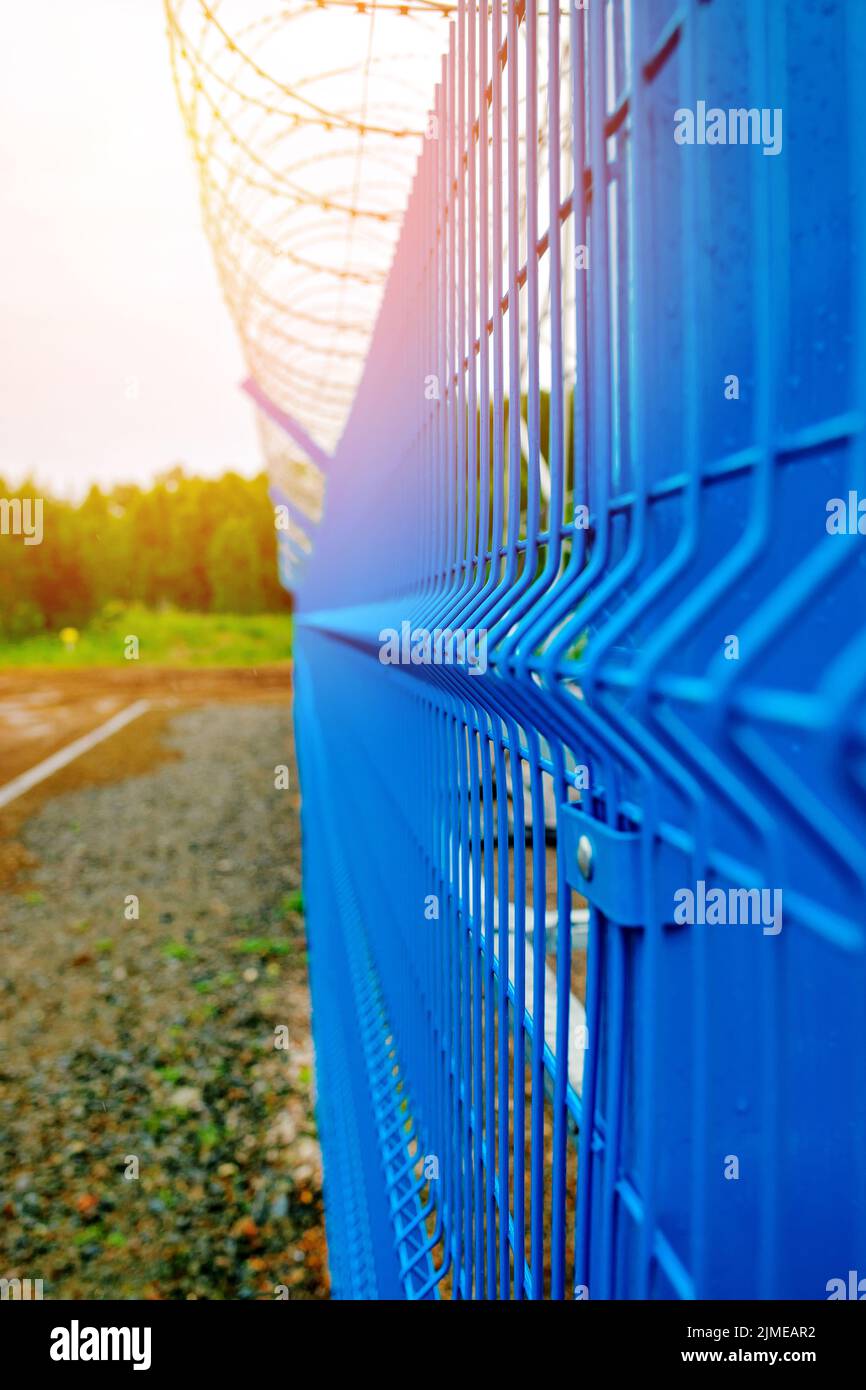 Metal fencing of the production facility with barbed wire around the perimeter. Stock Photo