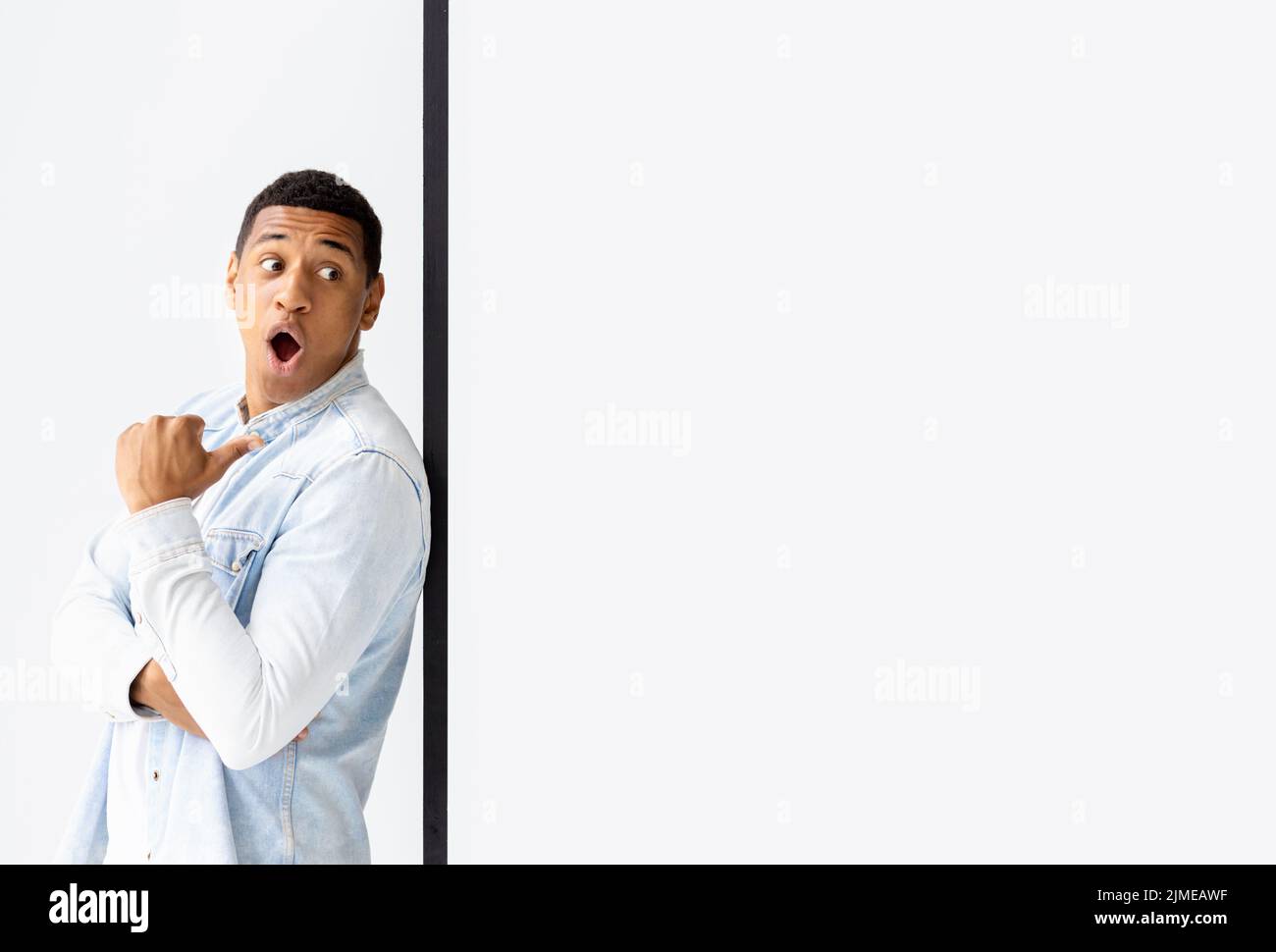 Mock-up Surprised young African American man pointing his finger at an empty white board copy space Stock Photo