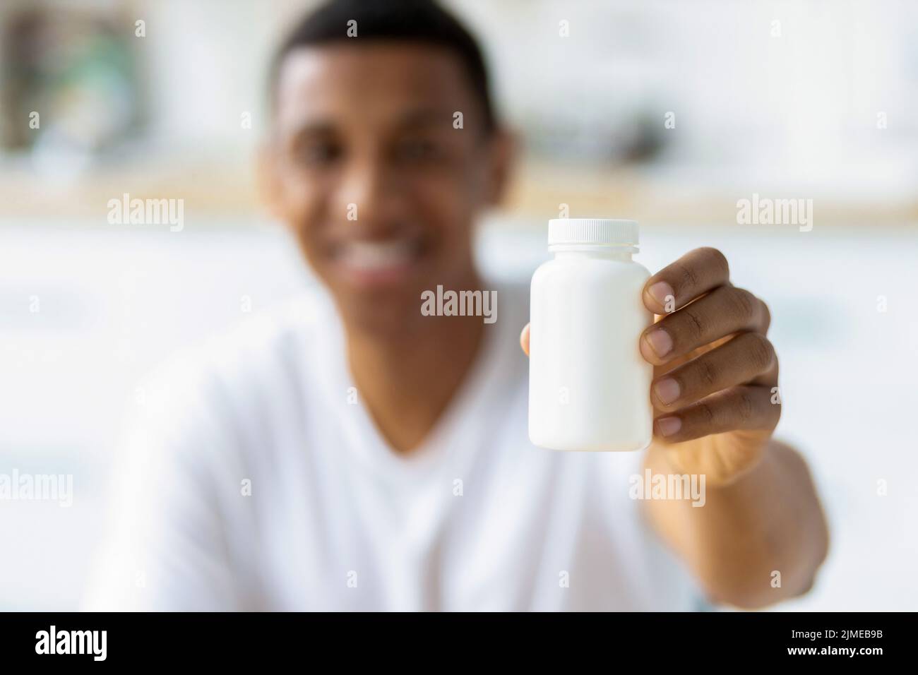 Happy young african american man holding capsules and open bottle