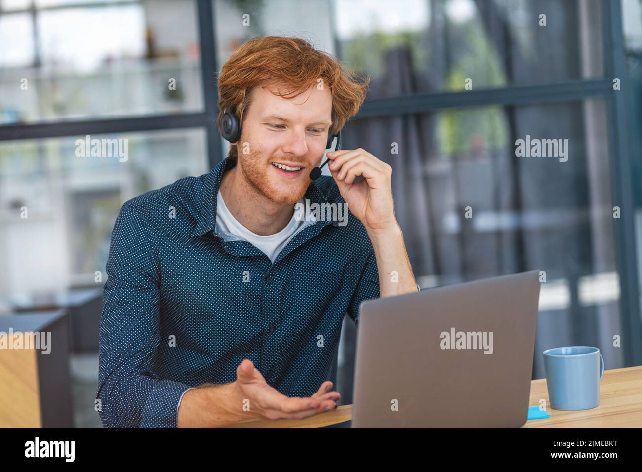young man customer support call center operator or receptionist sitting at the workplace in office consulting client Stock Photo