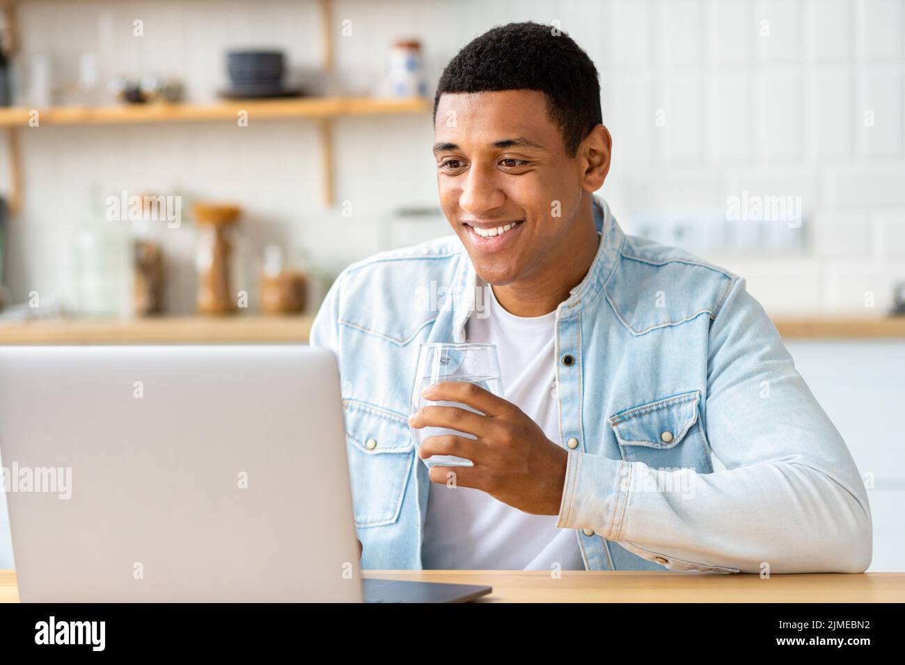 Young male student or freelancer uses laptop for online education or work Happy African American man working Stock Photo