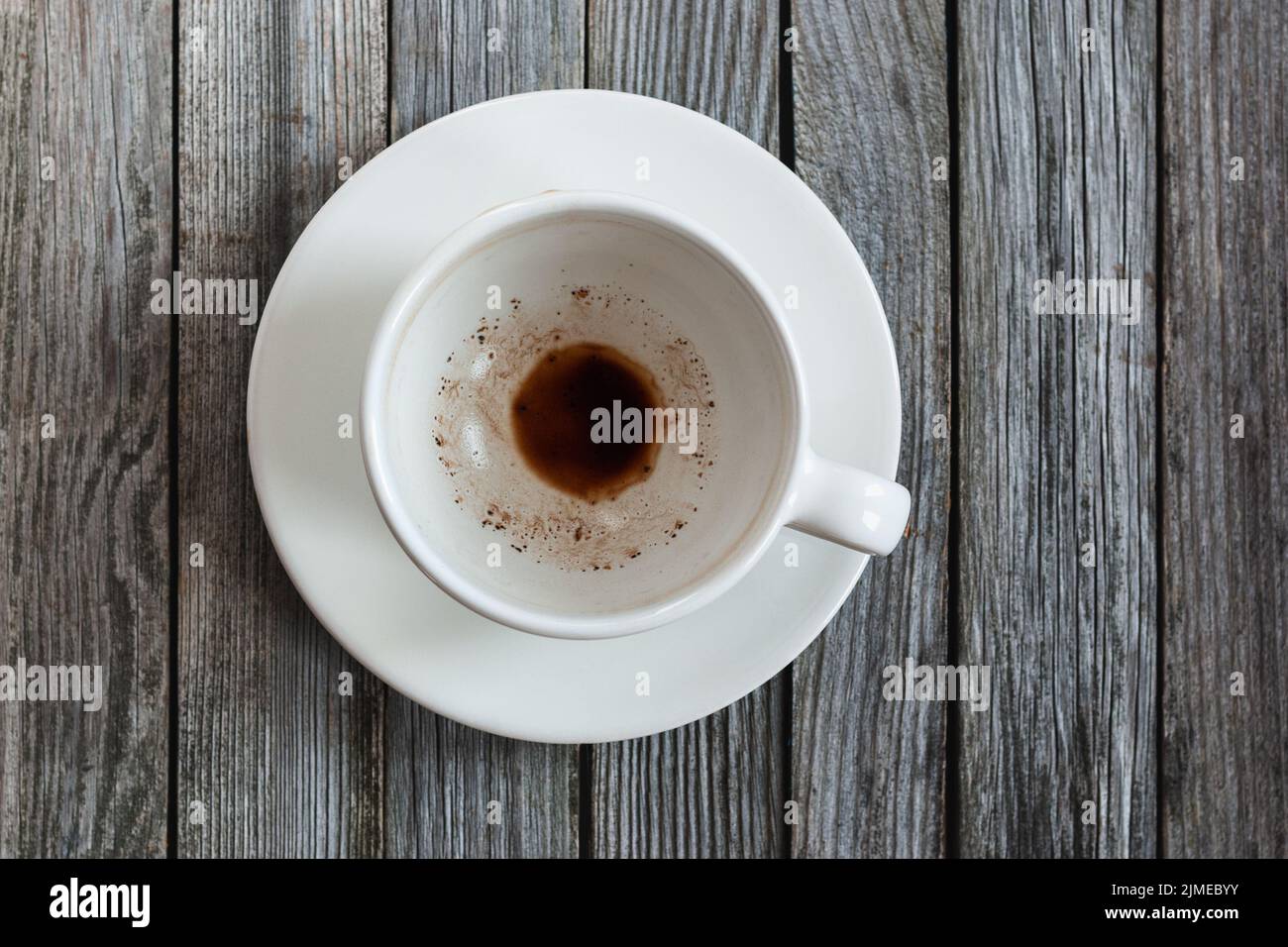 Empty cup with coffee leftovers on wooden table, closeup Stock Photo