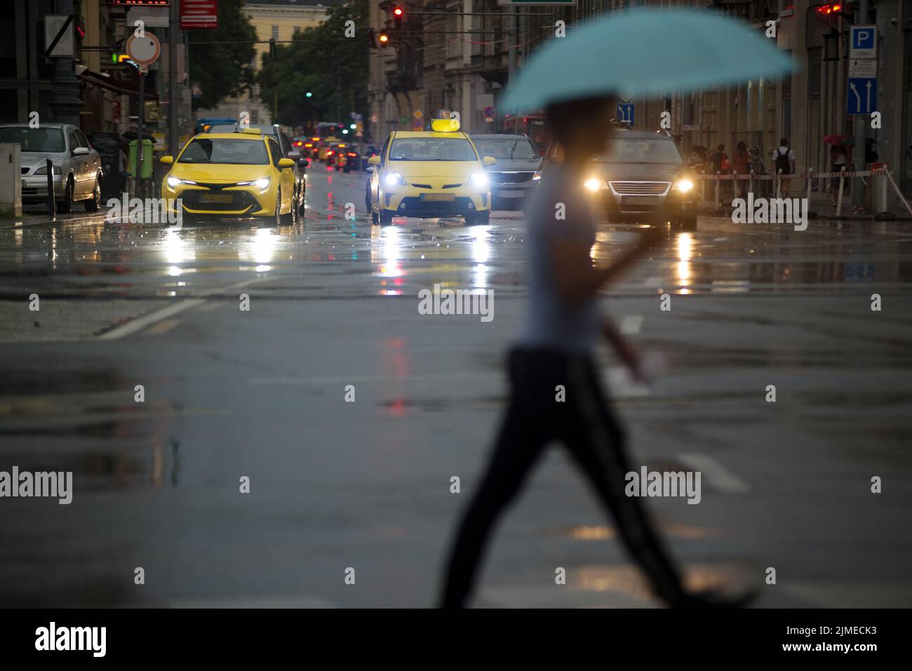 Unfocused person crossing street under umbrella Stock Photo
