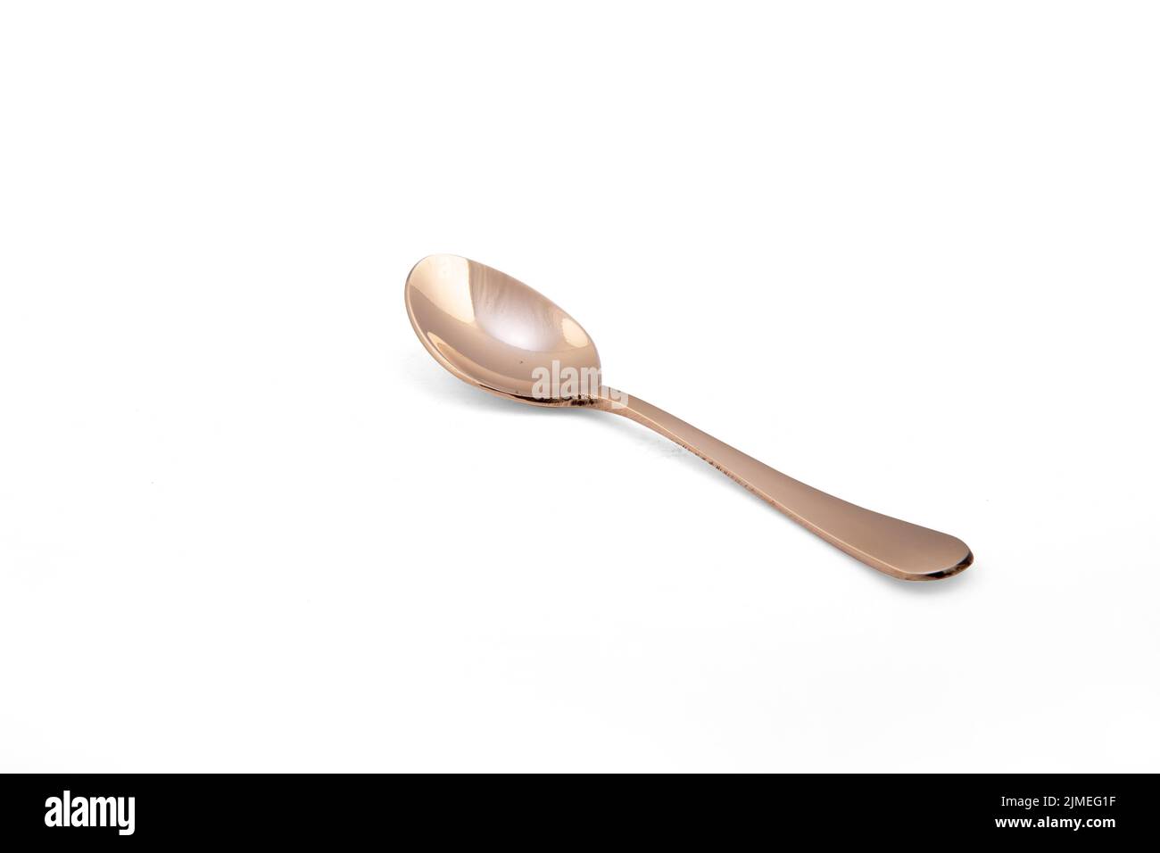 A bright shiny bronze spoon isolated on white background Stock Photo