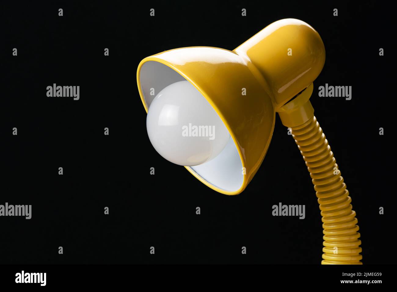 Side view of adjustable yellow desk lamp isolated on black background. Stock Photo