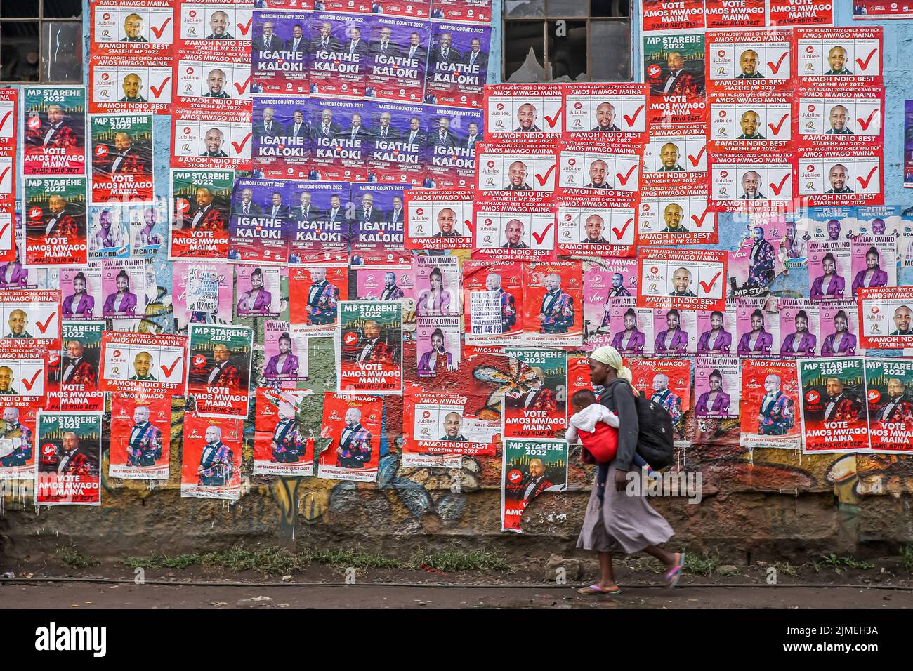 A woman carries her child as she walks past political campaign posters along Haile Selassie avenue in Nairobi, as Kenyans prepare to vote on the 9th August 2022 general elections. Politicians continue to campaign in different parts of the country to seek votes from Kenyans. Political campaign billboards, posters, branded cars, umbrellas, tshirts and banners are seen everywhere general elections campaign. Kenyans will head to the polls on August 9, 2022, to elect a new president, as well as members of the National Assembly and Senate, county governors, county woman representatives and members o Stock Photo