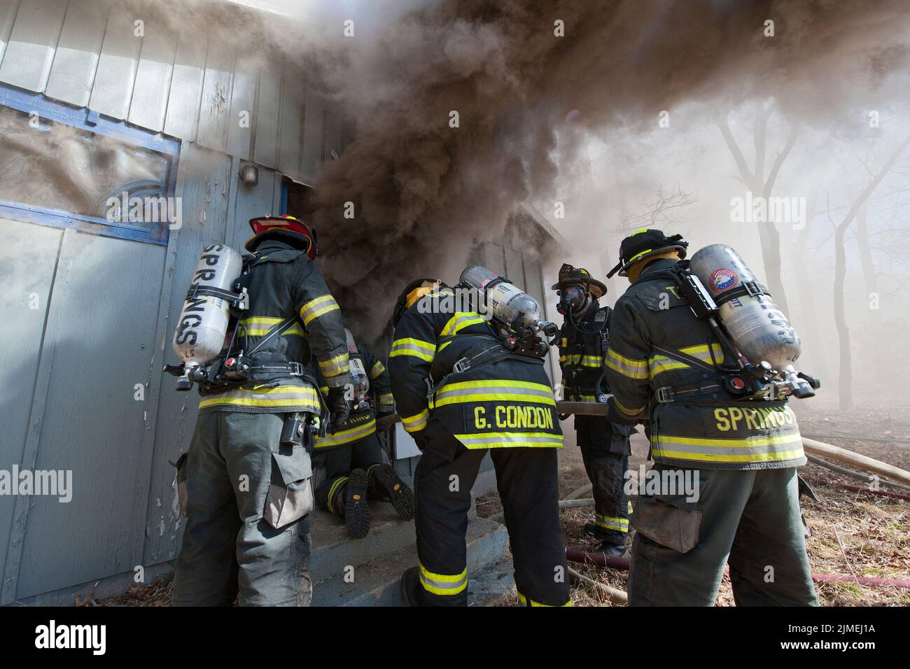 Members of the East Hampton Fire Department and the Springs Fire Department enter a building as they held a joint live-burn training drill in three ol Stock Photo