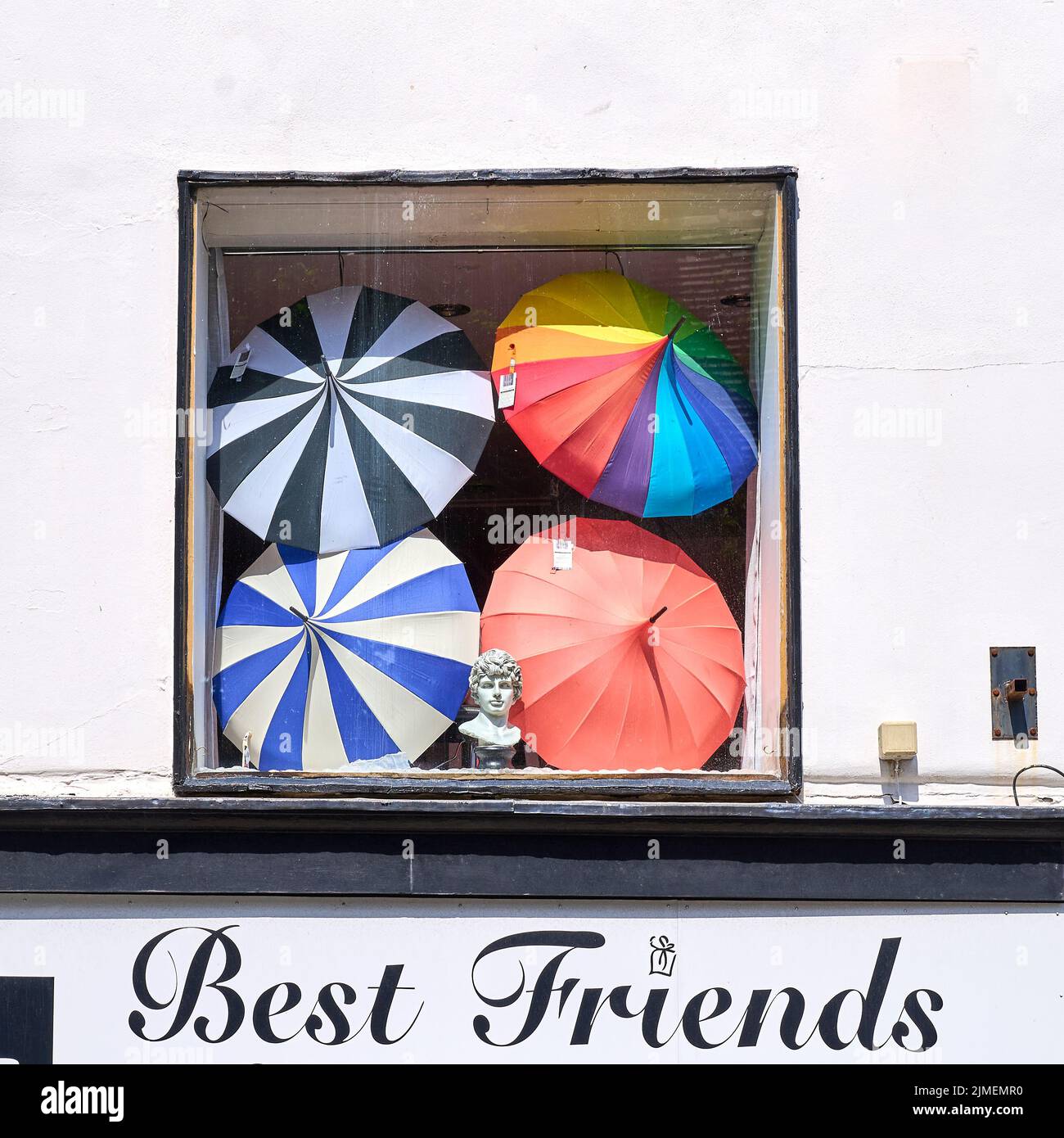 Multi-coloured parasols in window of  shop with black and white frontage Stock Photo