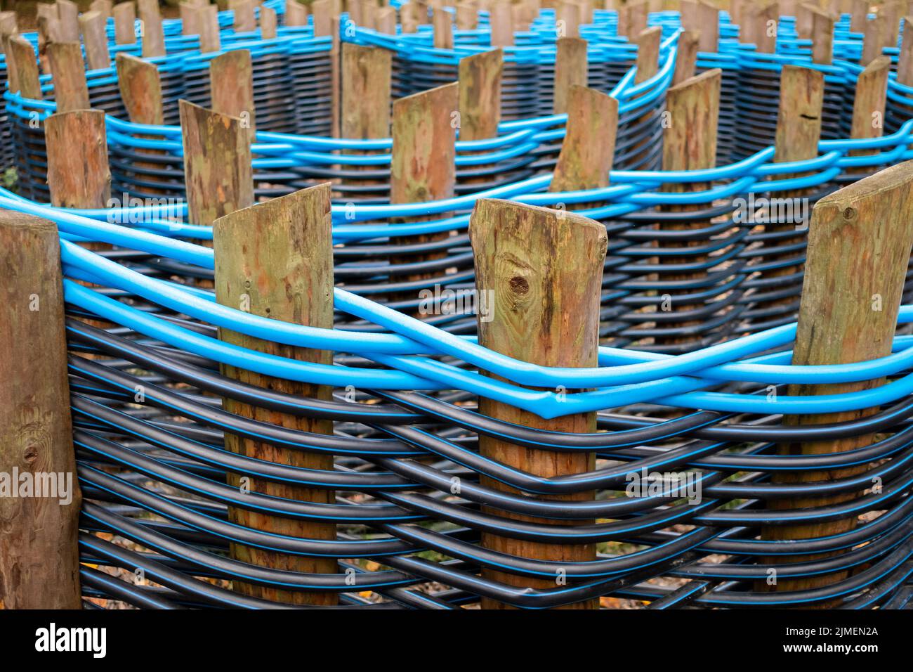 Fence of plastic pipes intertwined between wooden poles Stock Photo Alamy