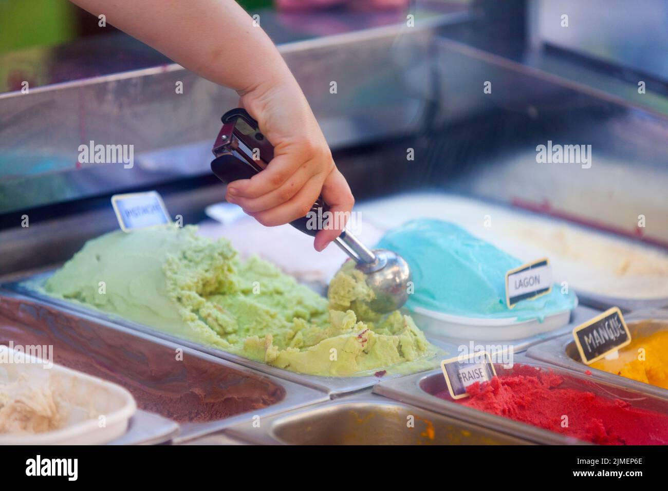 Close up on the hand of a young waman scooping an ice cream in gelato cafe. Stock Photo
