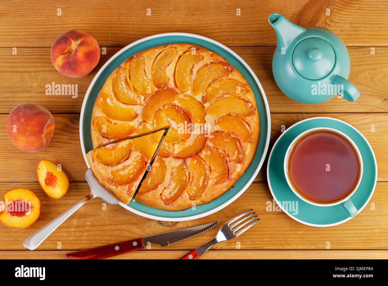 Homemade pie with peaches and cup of tea on wooden table. Top view. Stock Photo