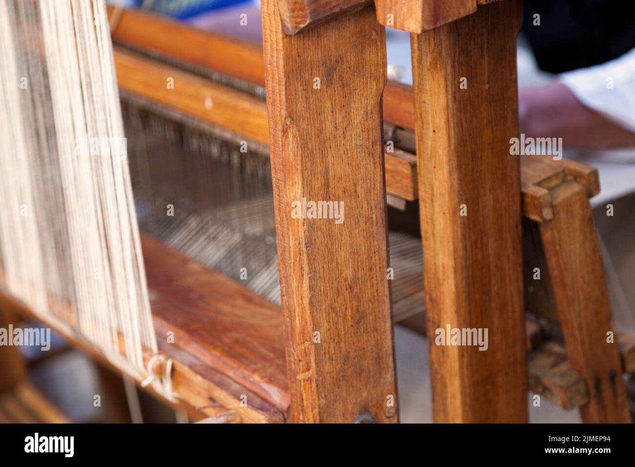 Man weaving a canvas from flax fibers with an antique hand weave machine. Stock Photo