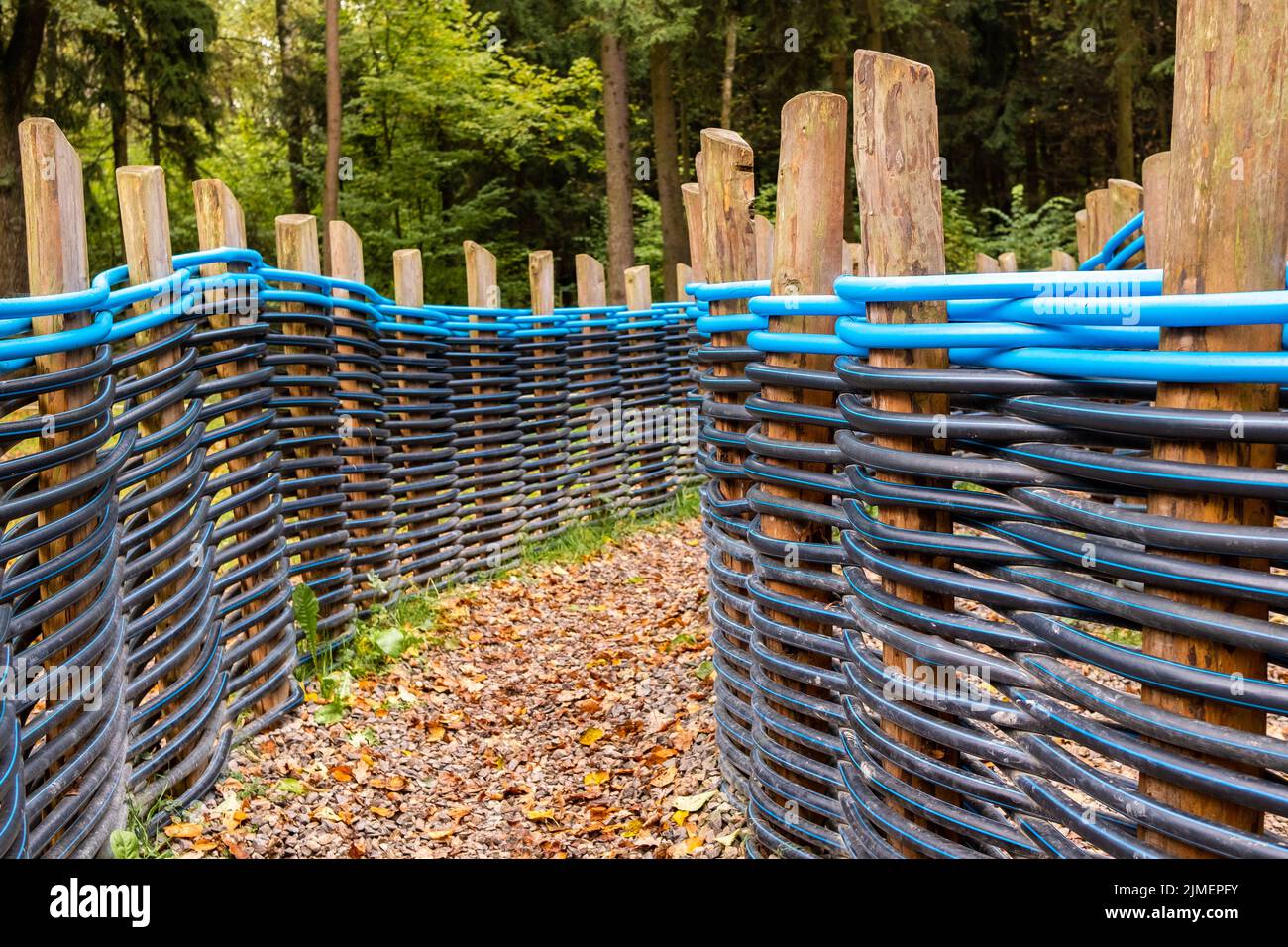 Fence of plastic pipes intertwined between wooden poles. Stock Photo