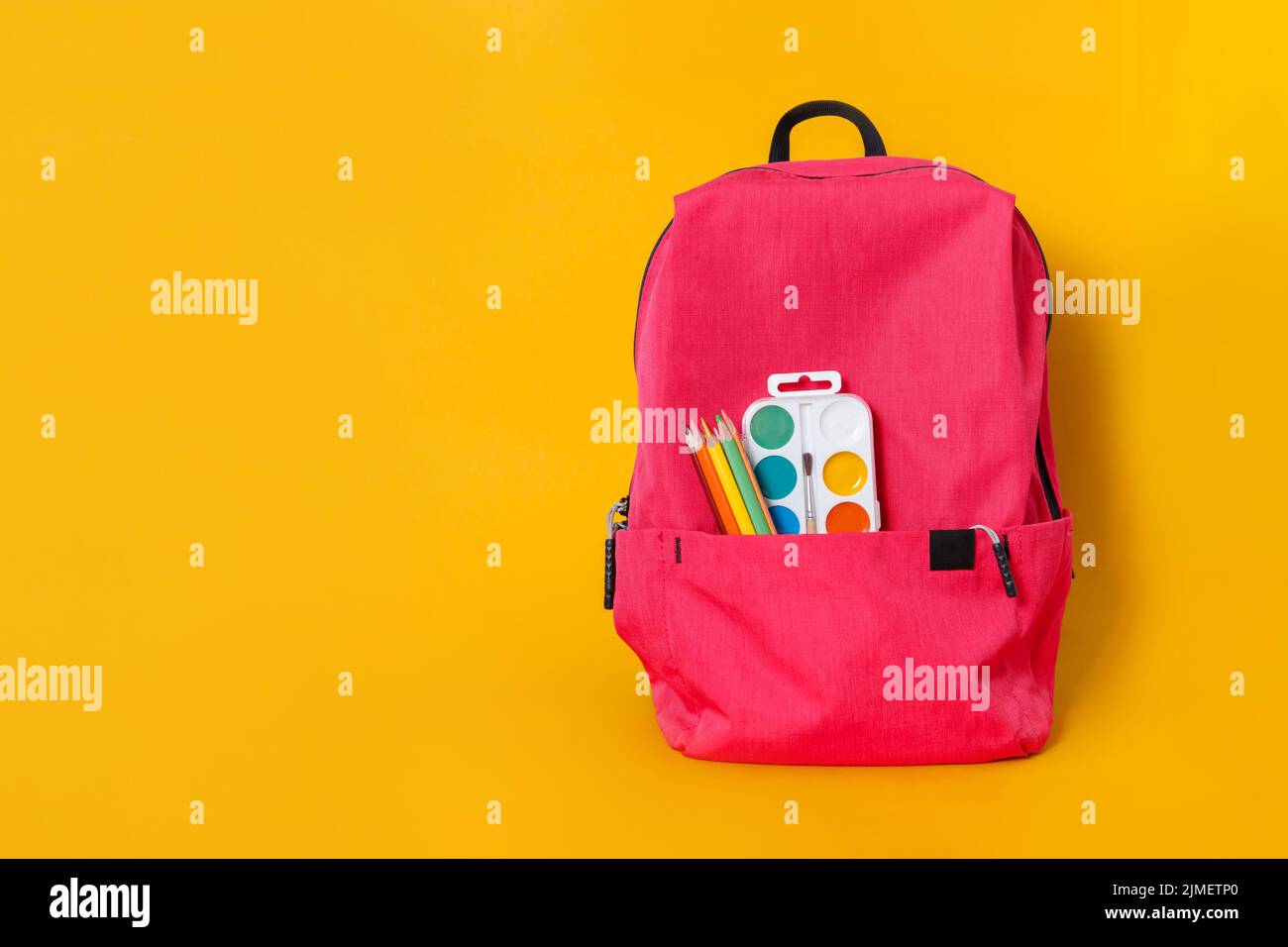 Back to school, backpack with school supplies and stationery on yellow