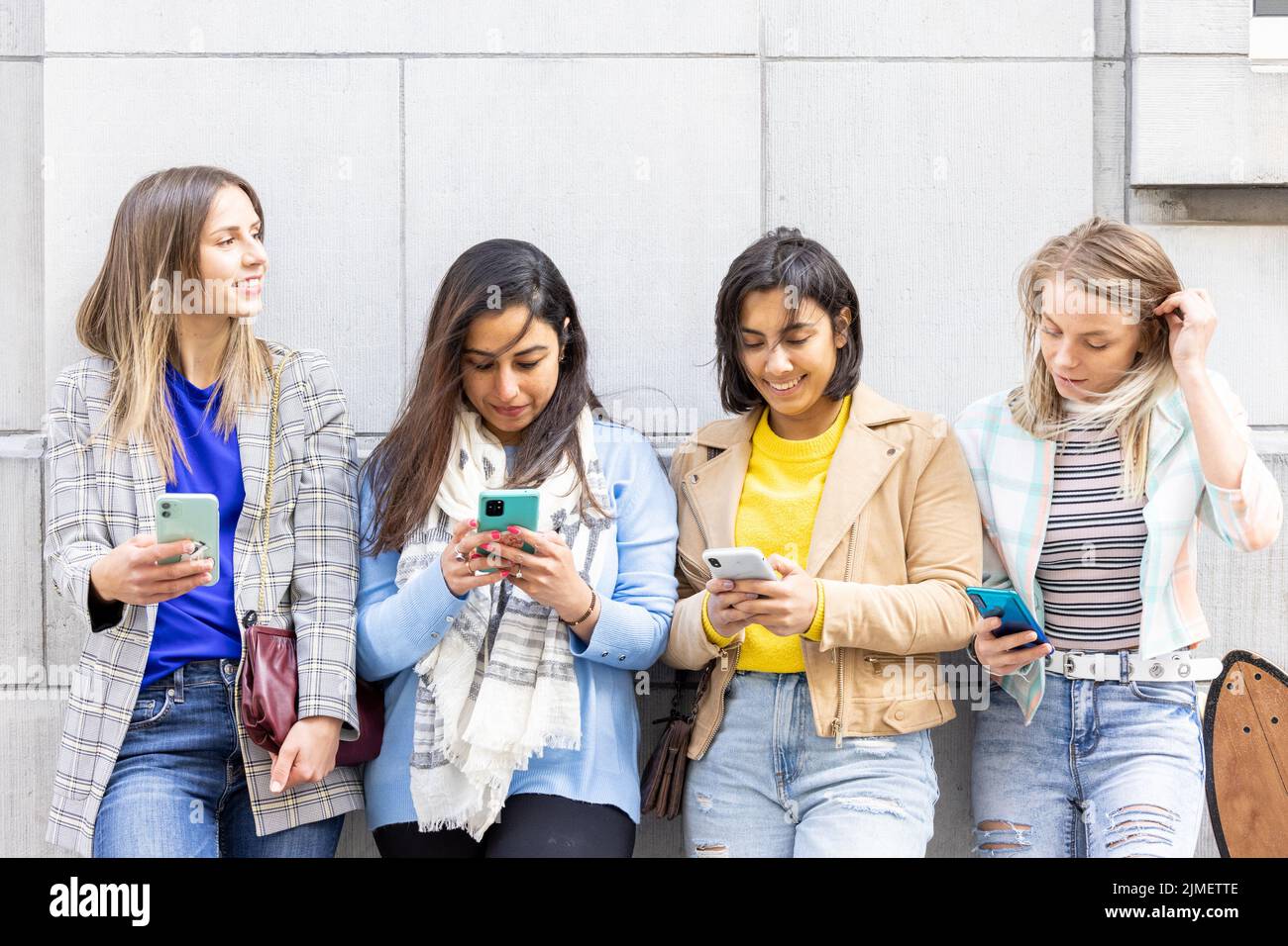 Multiracial group of teenagers have fun playing happily with smartphones. Use by millennials of cell phones and social applicati Stock Photo