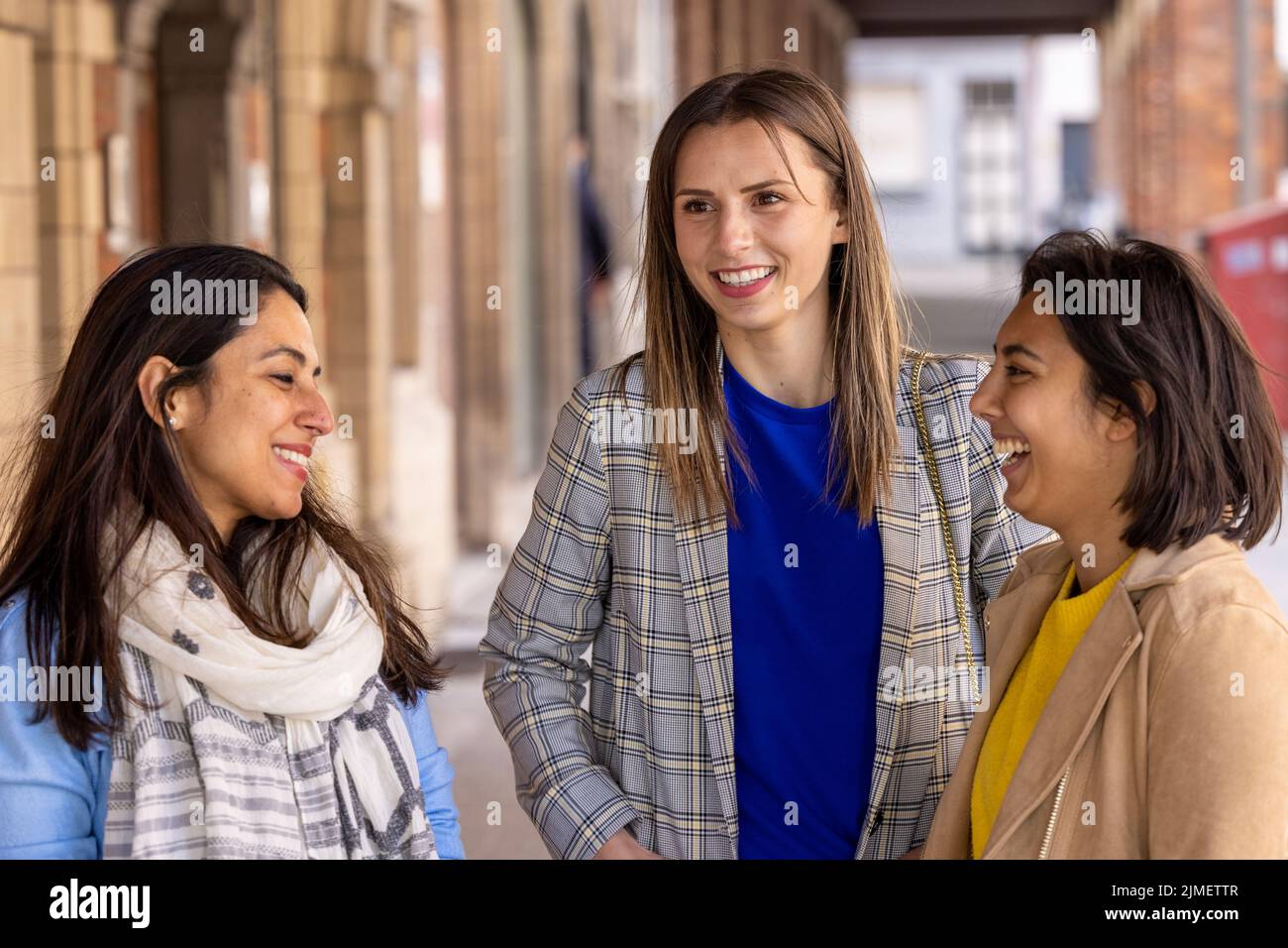 Multiracial group of girls walking in the city. Urban background with busy road and sidewalk, friendship and lifestyle concepts. Stock Photo