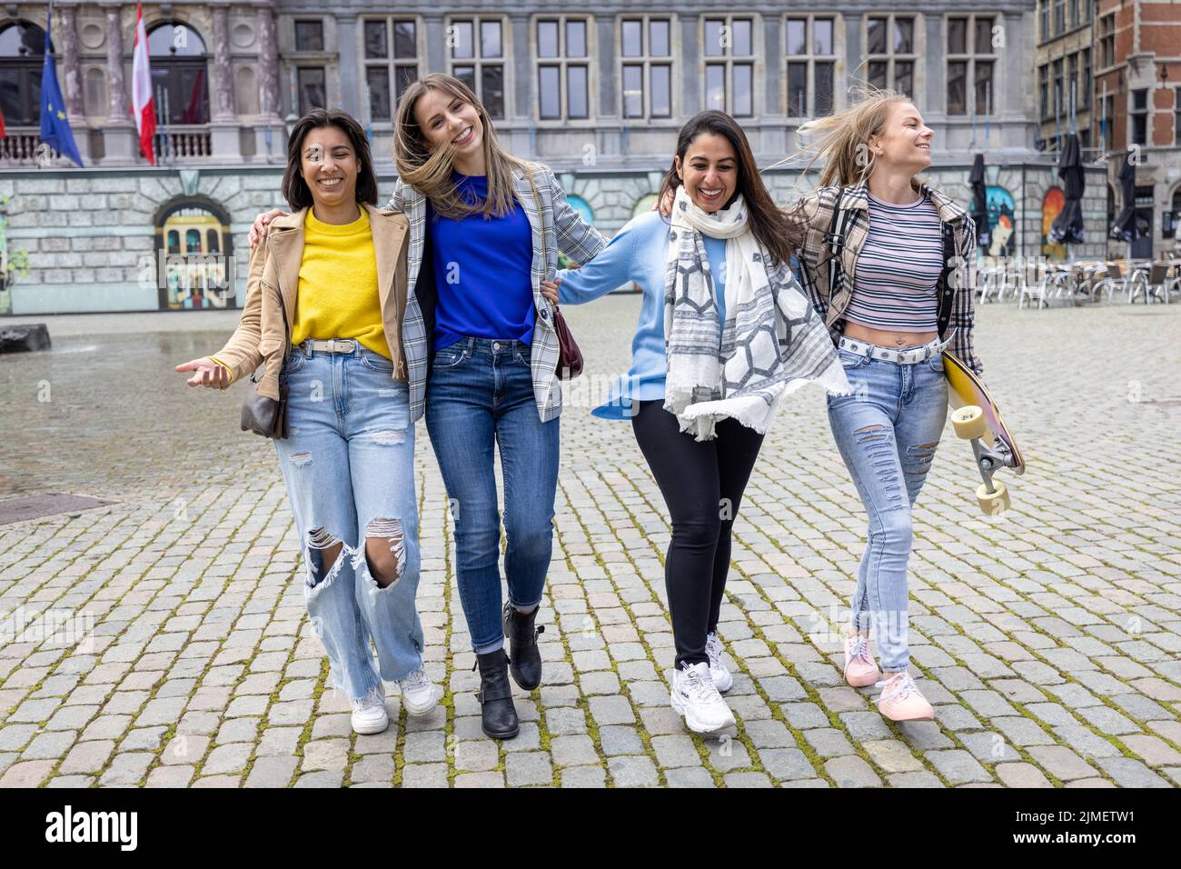 Mixed race group of attractive young women smiling, hugging and walking in the city center of Antwerp. urban lifestyle Stock Photo