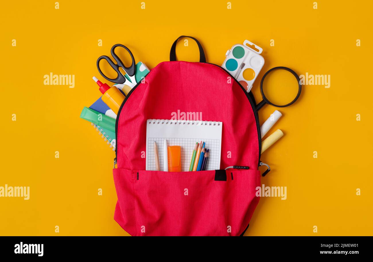Back to school, backpack with school supplies and stationery on yellow