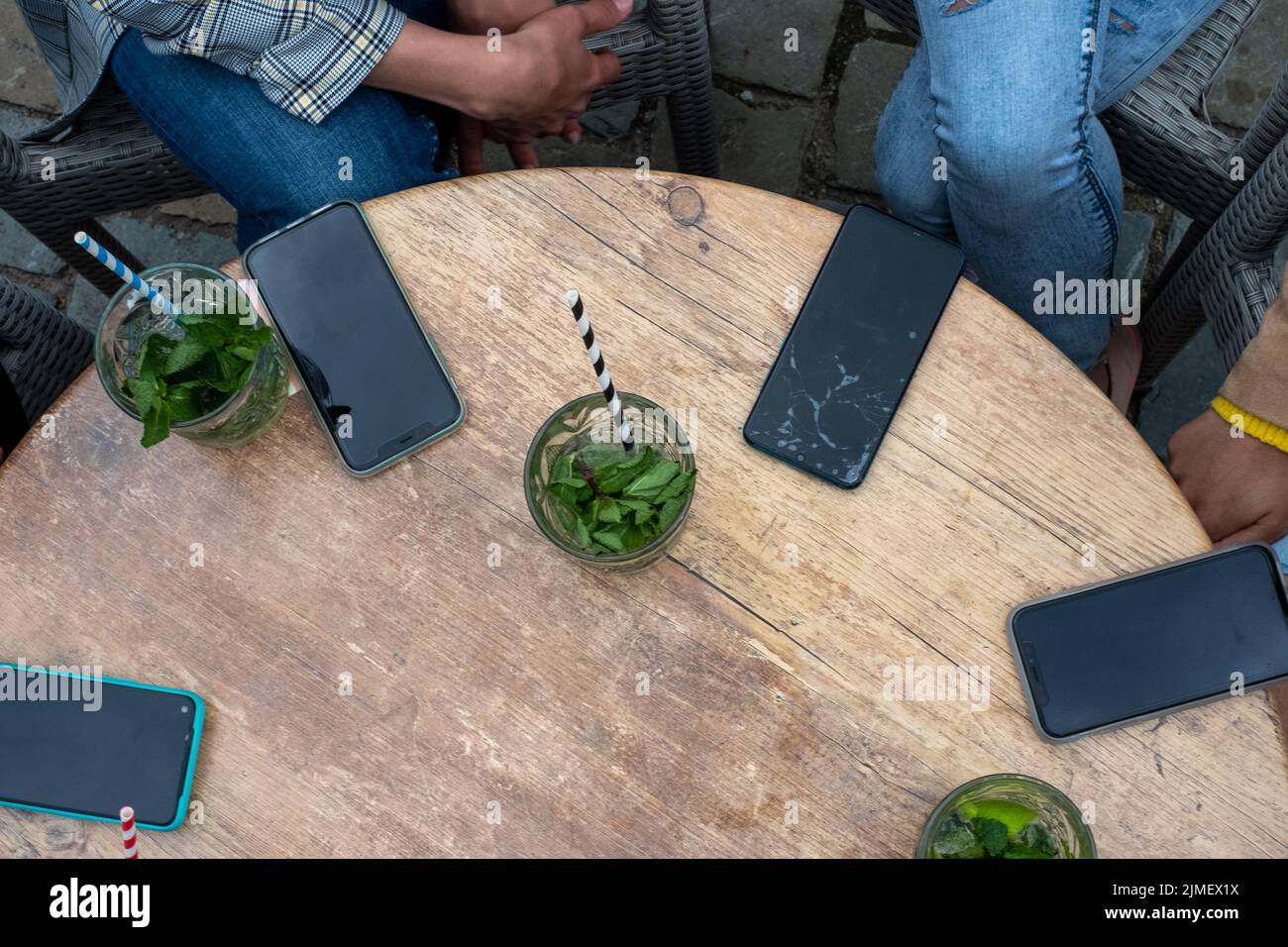 Group of females having their smartphones down on a table while enjoying a cocktail and company. Women online together. top view Stock Photo