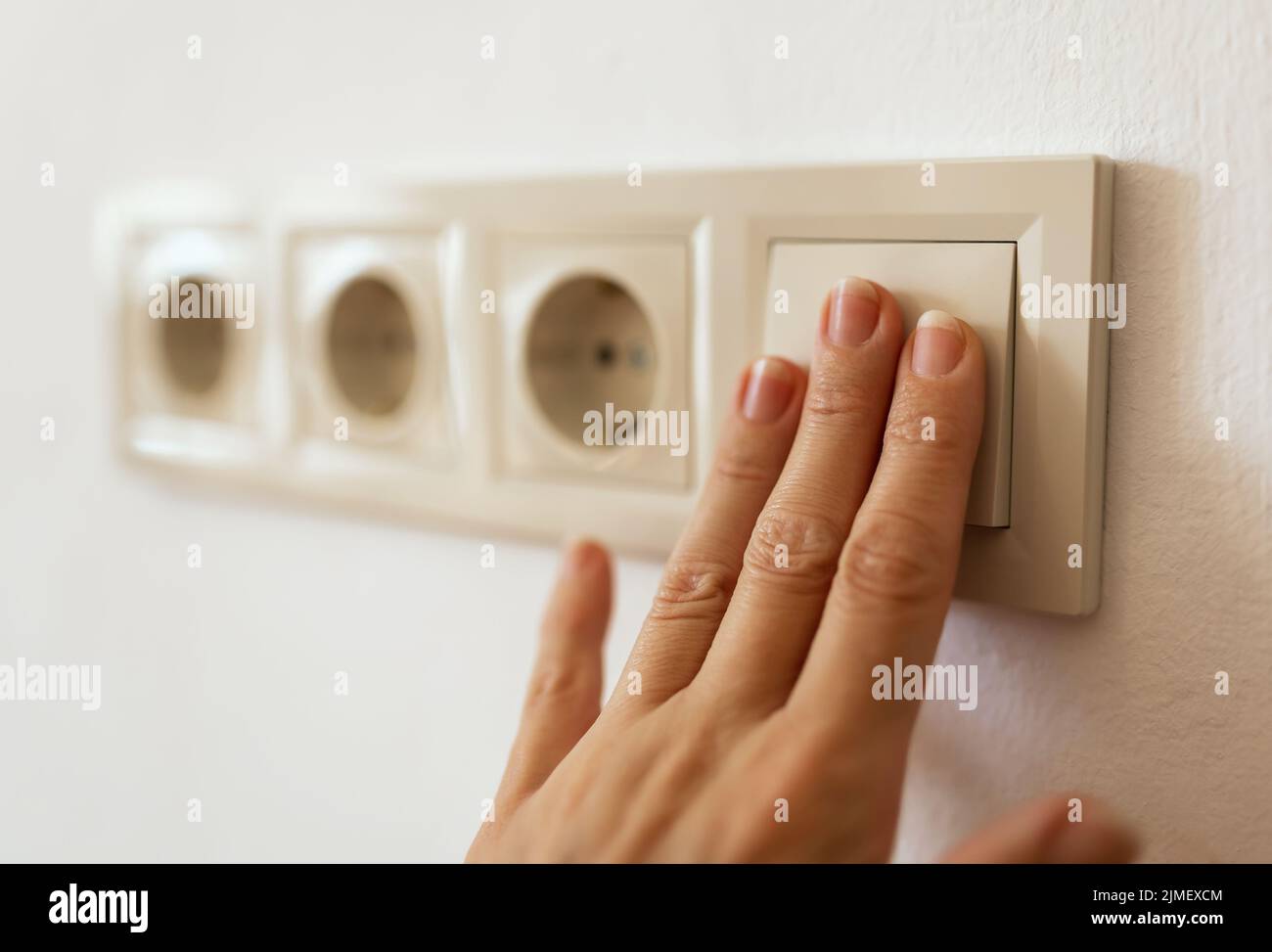 Fingers turn on or off light switch. Saving energy, electricity, power ...