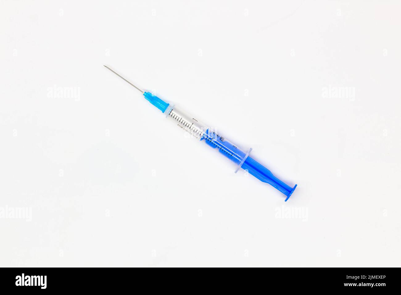Blue medical disposable syringe for injection on a white background. Medical instrument for vaccination. 2 ml syringe for COVID-19 vaccine. Medical Stock Photo