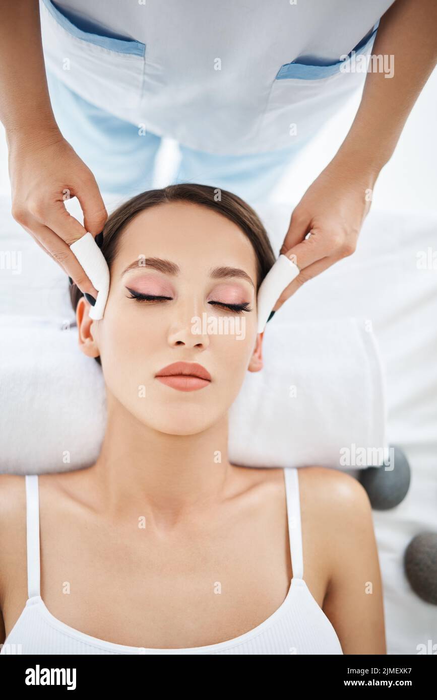 Beautiful caucasian woman enjoying facial spa procedure in salon Stock
