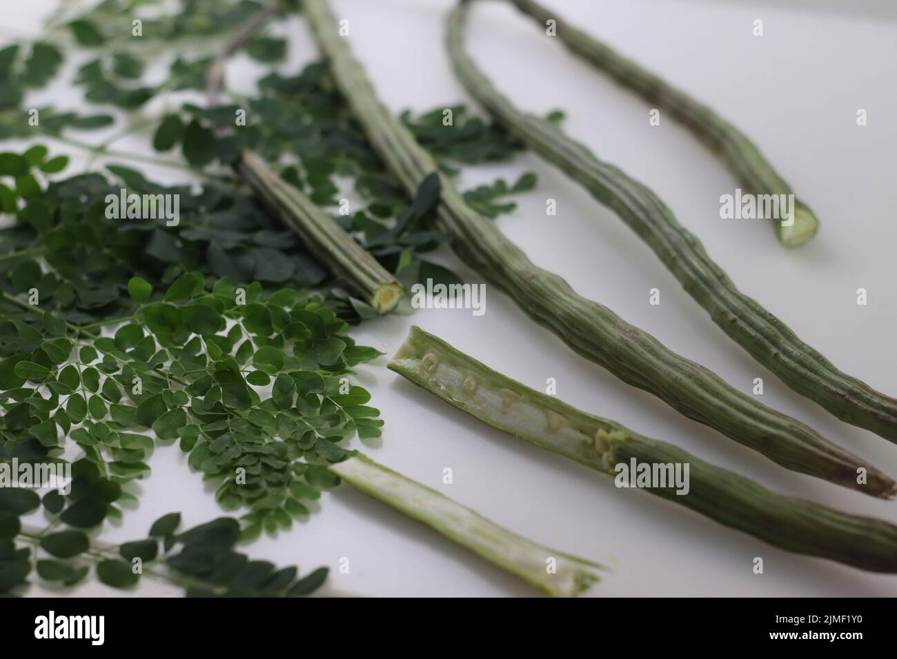 Drum stick or moringa. It is a superfood with many nutrition value. Shot along with moringa leaves on white background. Stock Photo