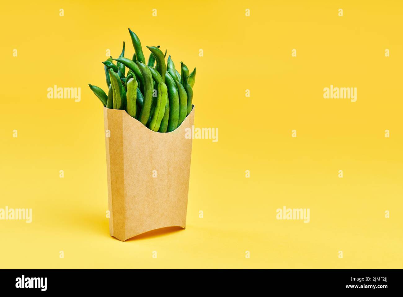 Fresh green beans in fast food paper box on bright yellow background with copy space Stock Photo