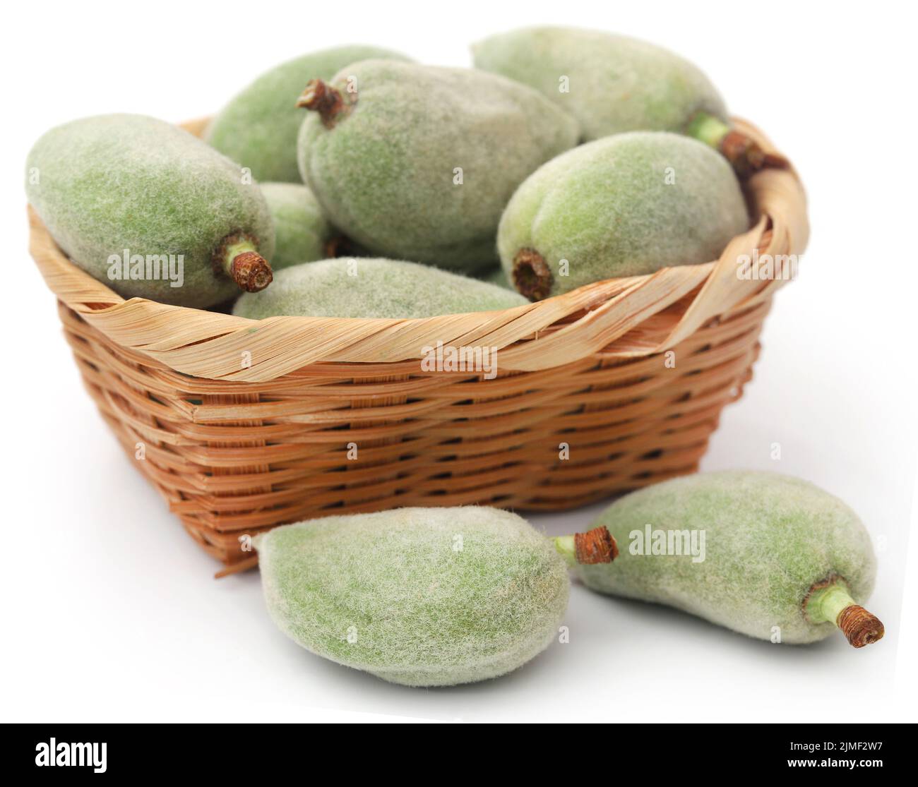 Green almond in basket over white background Stock Photo