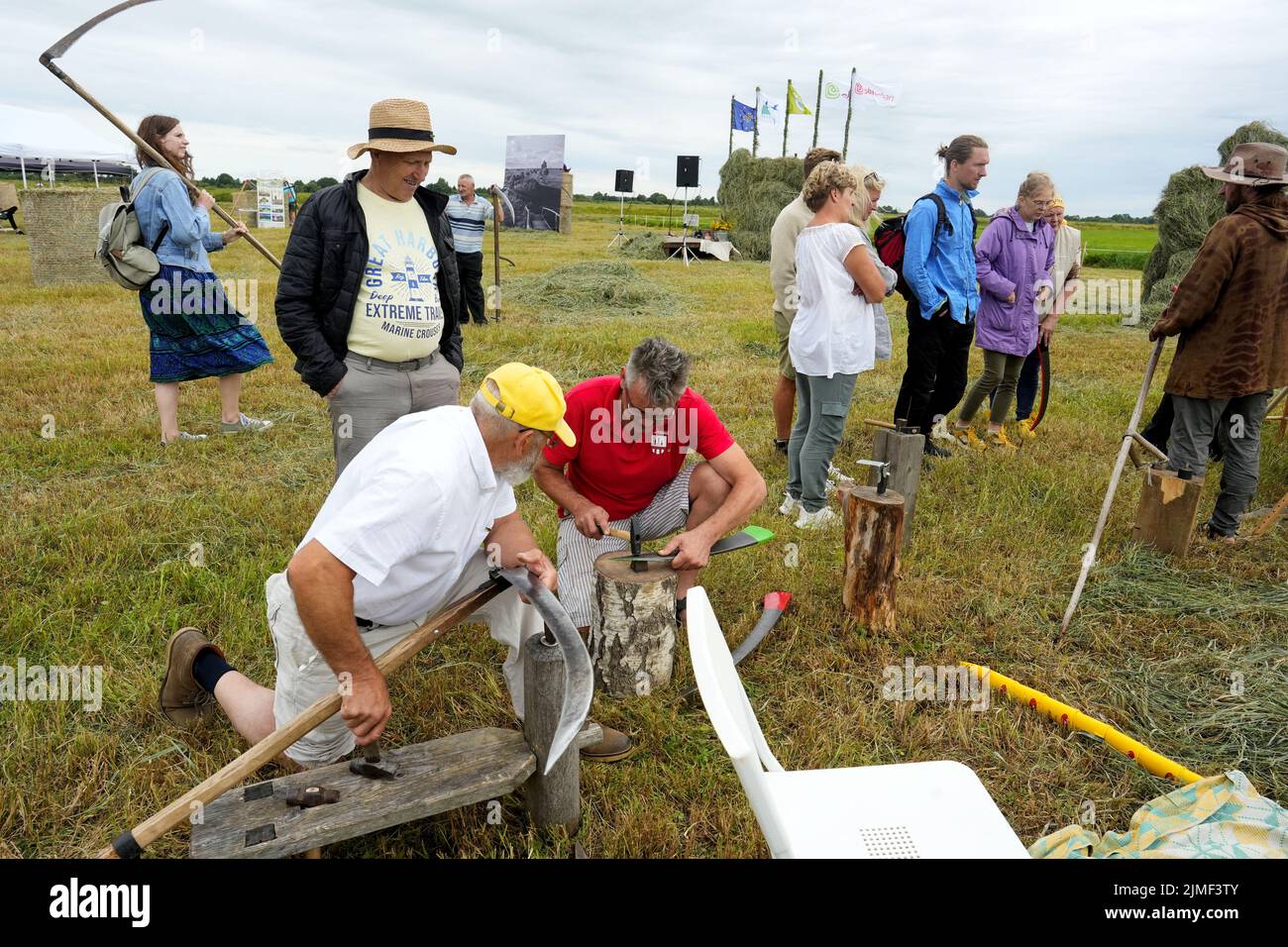 Men prepare scythes during Lithuanian mowing championship to cut down grass using scythes in Rupkalviai, Lithuania  August 6, 2022. REUTERS/Ints Kalnins Stock Photo