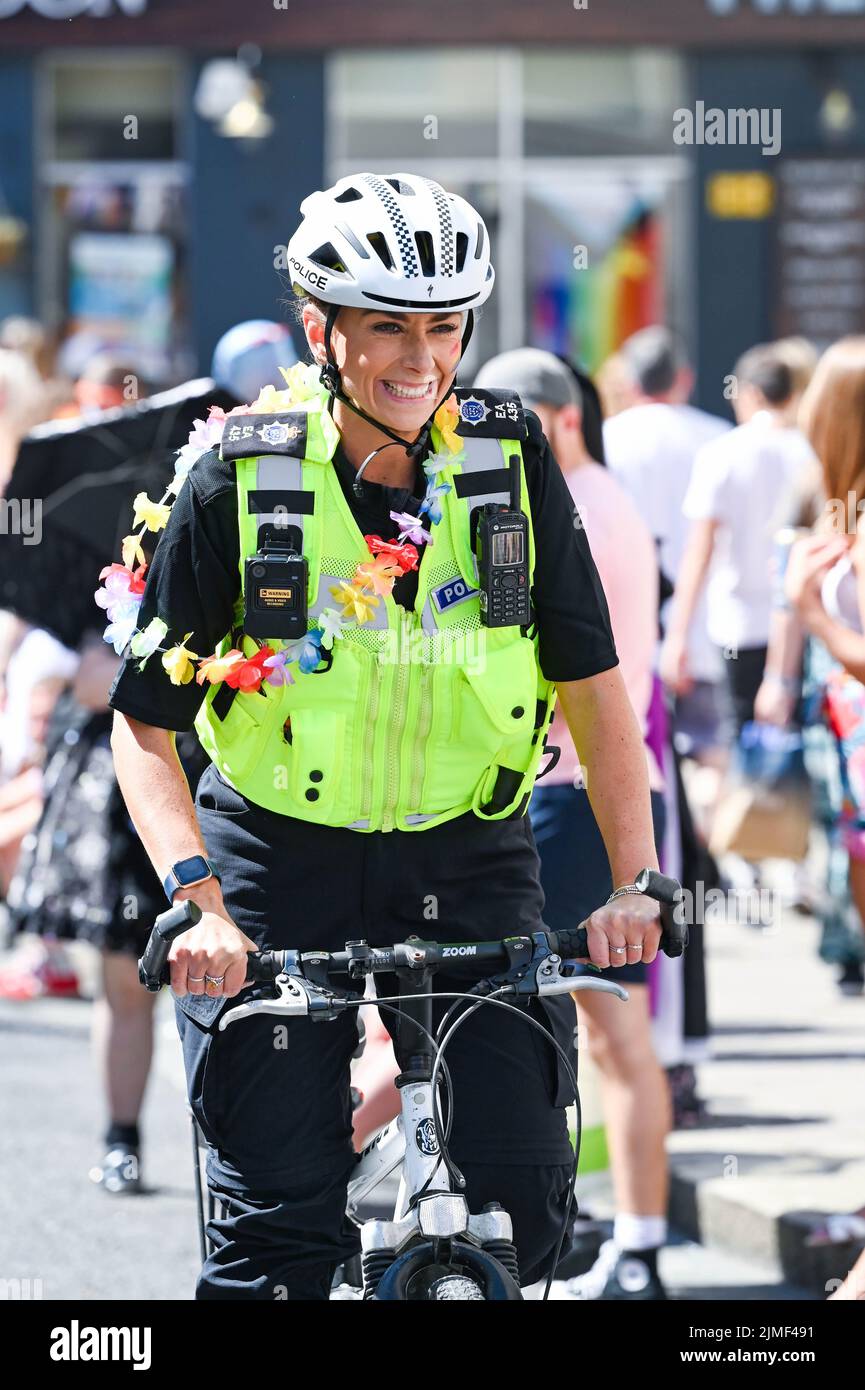 Brighton UK 6th August 2022 - A cycling police officer tries to keep up as thousands take part in the  Brighton and Hove Pride Parade on a beautiful hot sunny day. With good weather forecast large crowds are expected to attend the UK's biggest LGBTQ Pride festival in Brighton over the weekend : Credit Simon Dack / Alamy Live News Stock Photo