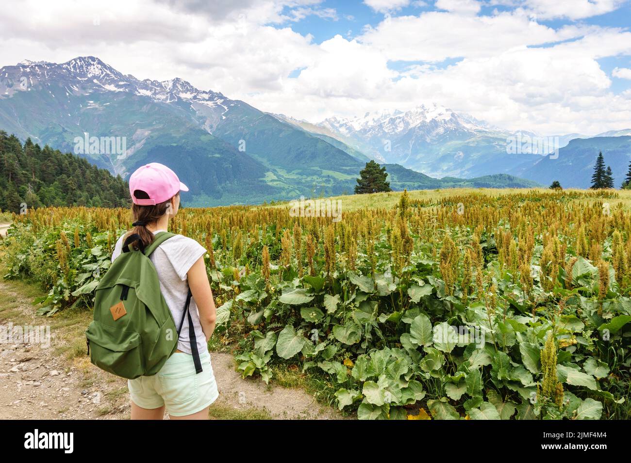 Svaneti landscape on a Summer day. Young tourist woman with a backpack overlooking Caucasus mountain range near Mestia Stock Photo