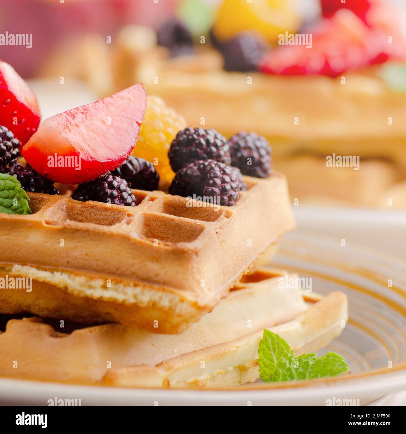 CLoseup view at belgian waffles served with strawberries and blackberries on kitchen table Stock Photo