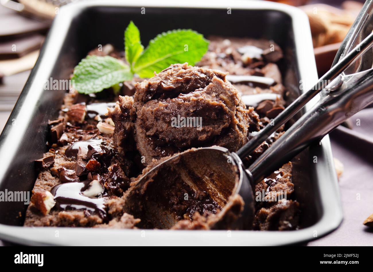 Chocolate icecream in metal tray with mint leaf and almond nuts Stock Photo