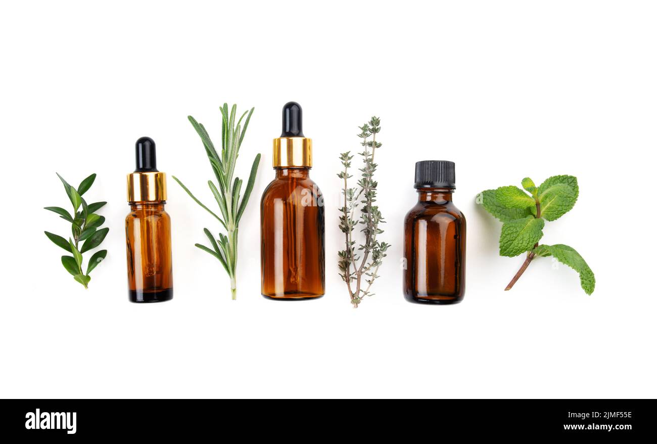 Dropper bottles with oil and herbs on white table flat lay view. Herbal cosmetics concept Stock Photo