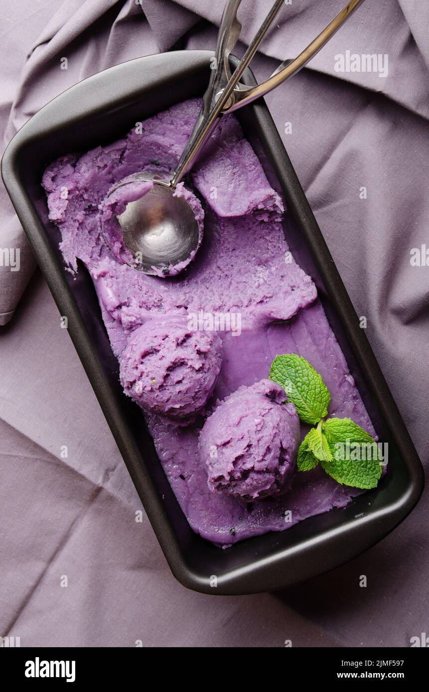 Flat lay view at blackberry icecream in metal tray served with mint leaf on kitchen table Stock Photo