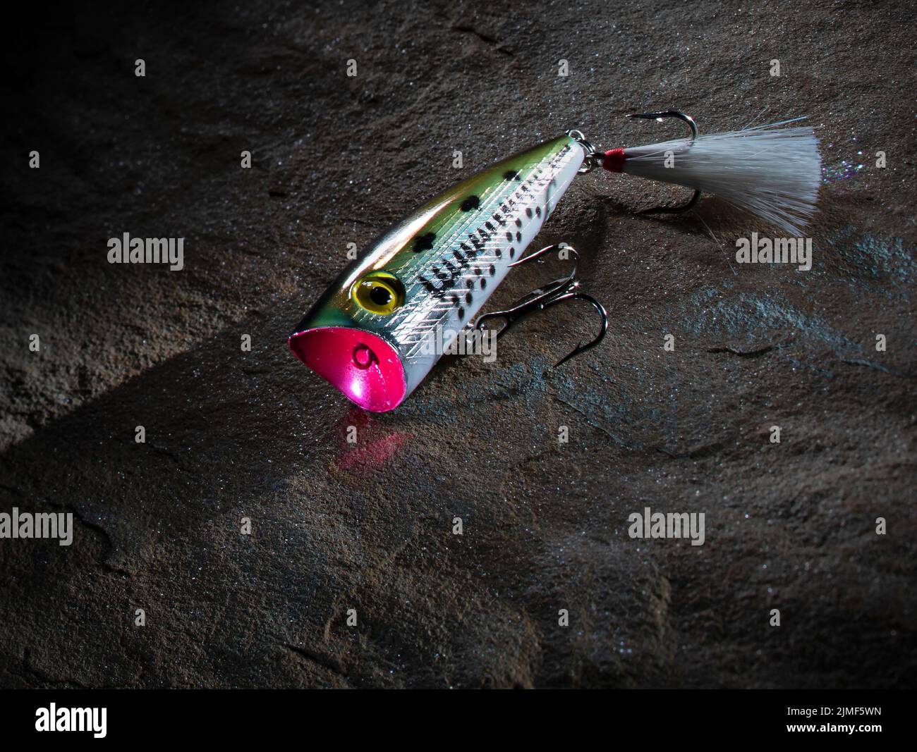 Topwater fishiing lure with treble hooks on a rock Stock Photo