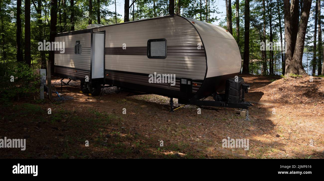 Camping trailer in a shady spot with Jordan Lake in the distance. Stock Photo