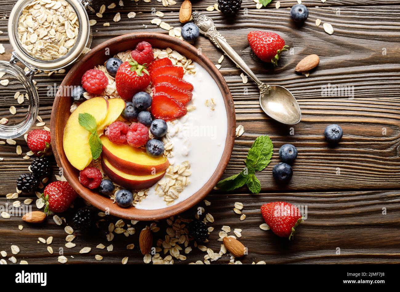 Flat lay of fruit healthy muesli with peaches strawberry almonds and blackberry in clay dish with yogurt Stock Photo