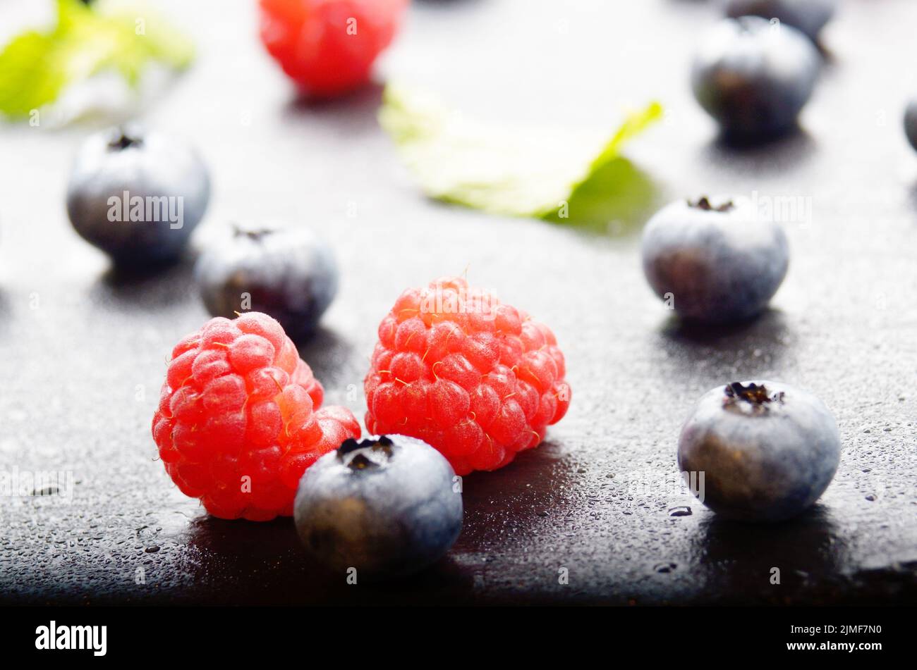 Ripe bilberry and raspberry berries on slate stone tray closeup Stock Photo