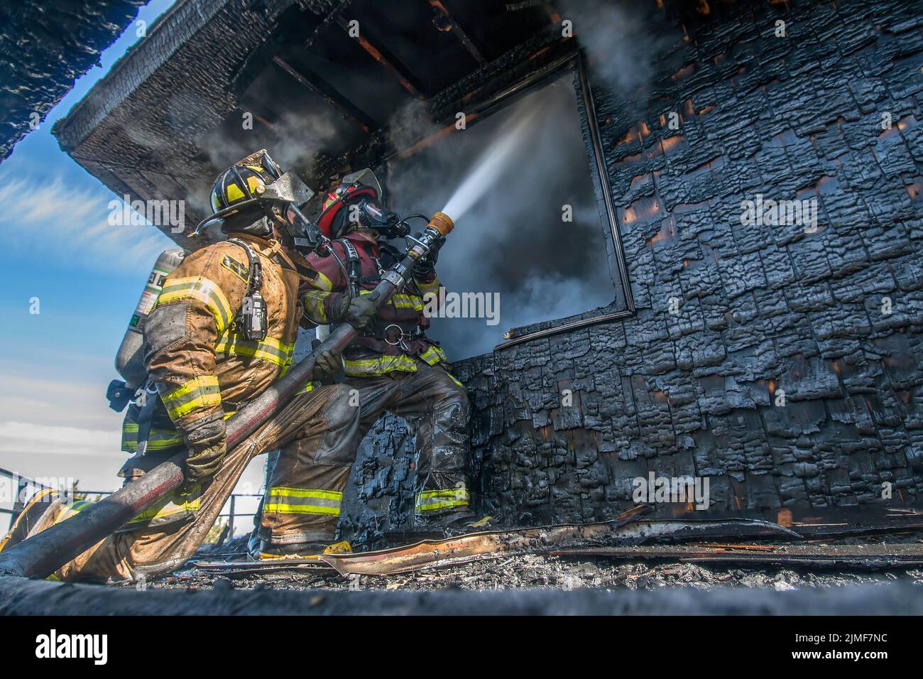Two Amagansett, New York firefighters shoot a hose stream through an open window as they attack a working house fire on Bendigo Road on February 16th, Stock Photo