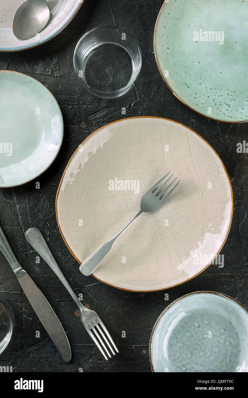 Modern tableware on a dark background. A plate with a fork and a glass, top shot Stock Photo