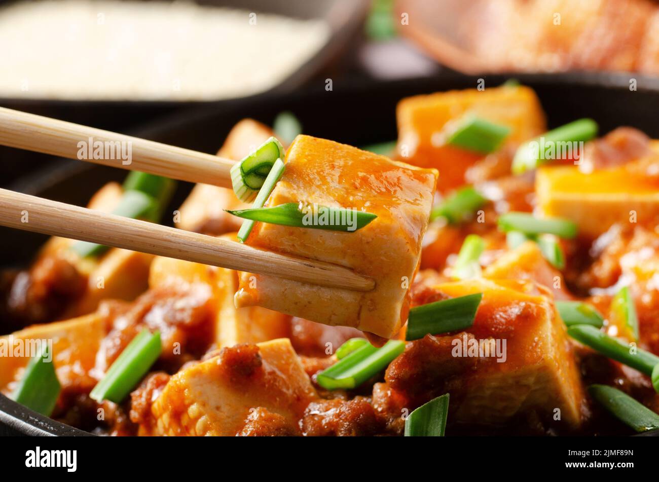 Mapo tofu dish of soybean curd piece being held in chopsticks Stock