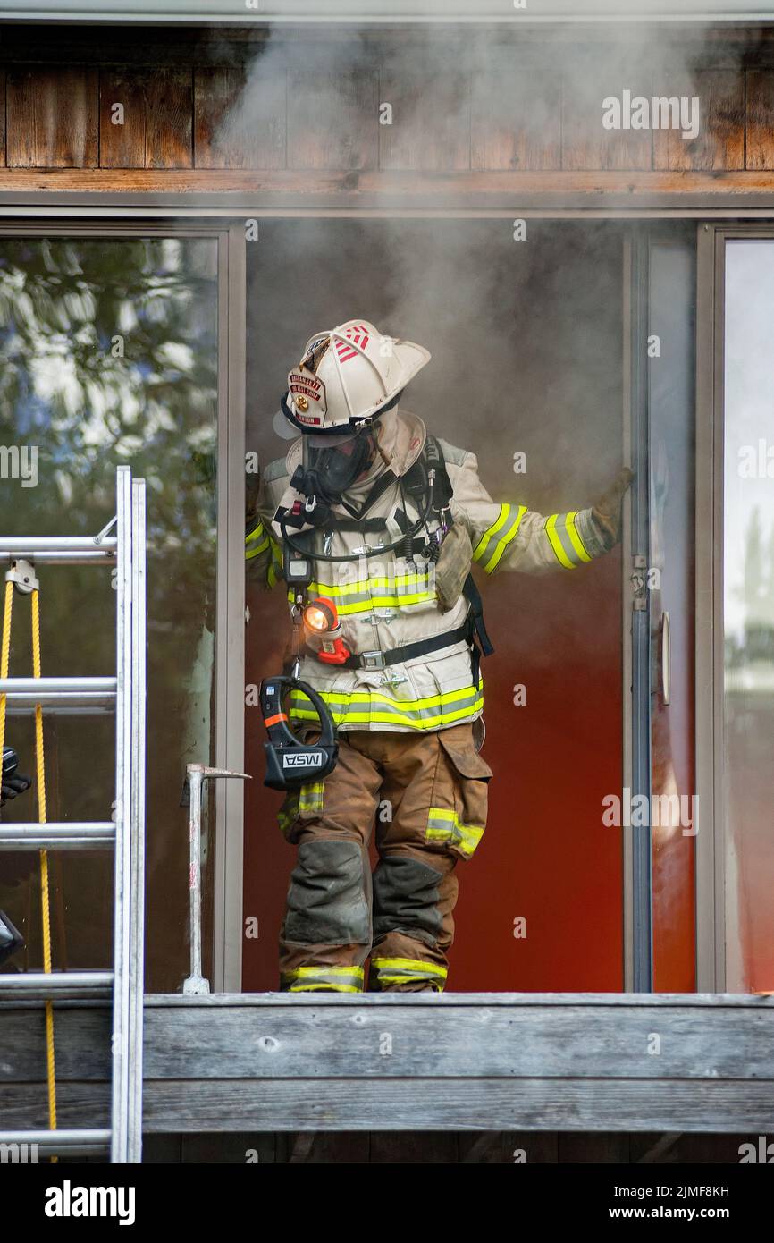 An Amagansett chief emerges from inside the building as the Amagansett Fire Department, along with members of the Montauk Fire Department, held a live Stock Photo